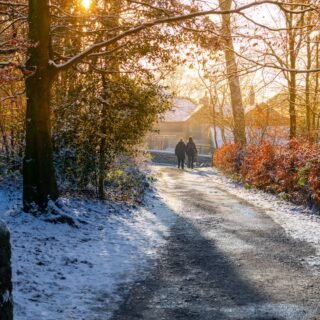 a couple of people walking down a snow covered road