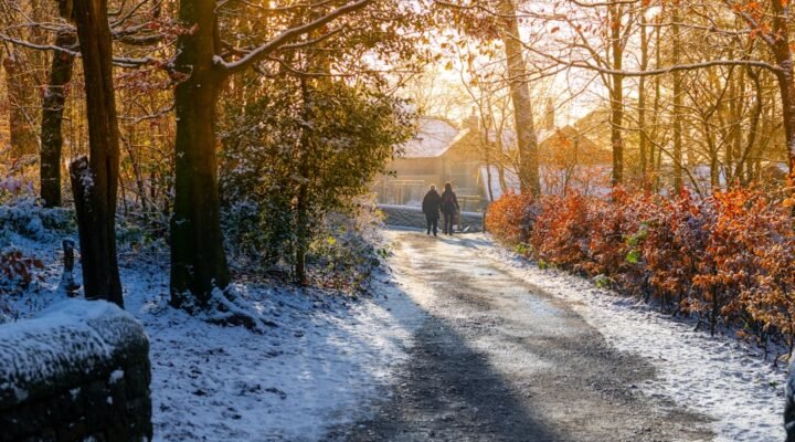 a couple of people walking down a snow covered road