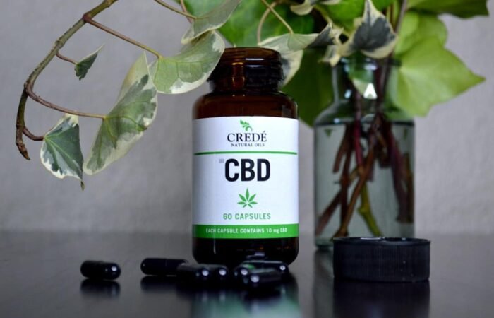 a bottle of cbd sitting next to a vase of flowers