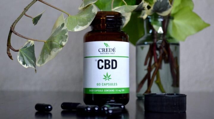 a bottle of cbd sitting next to a vase of flowers