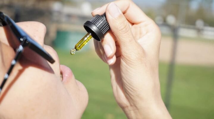 cbd oil flavors - Person examining different CBD oil bottles with various natural flavours
