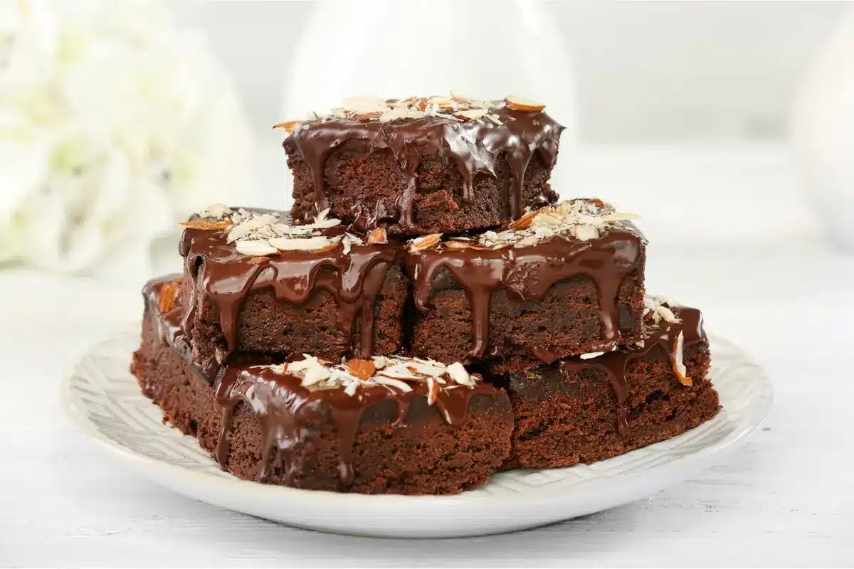 Chocolate brownies cut into squares and stacked on a white plate