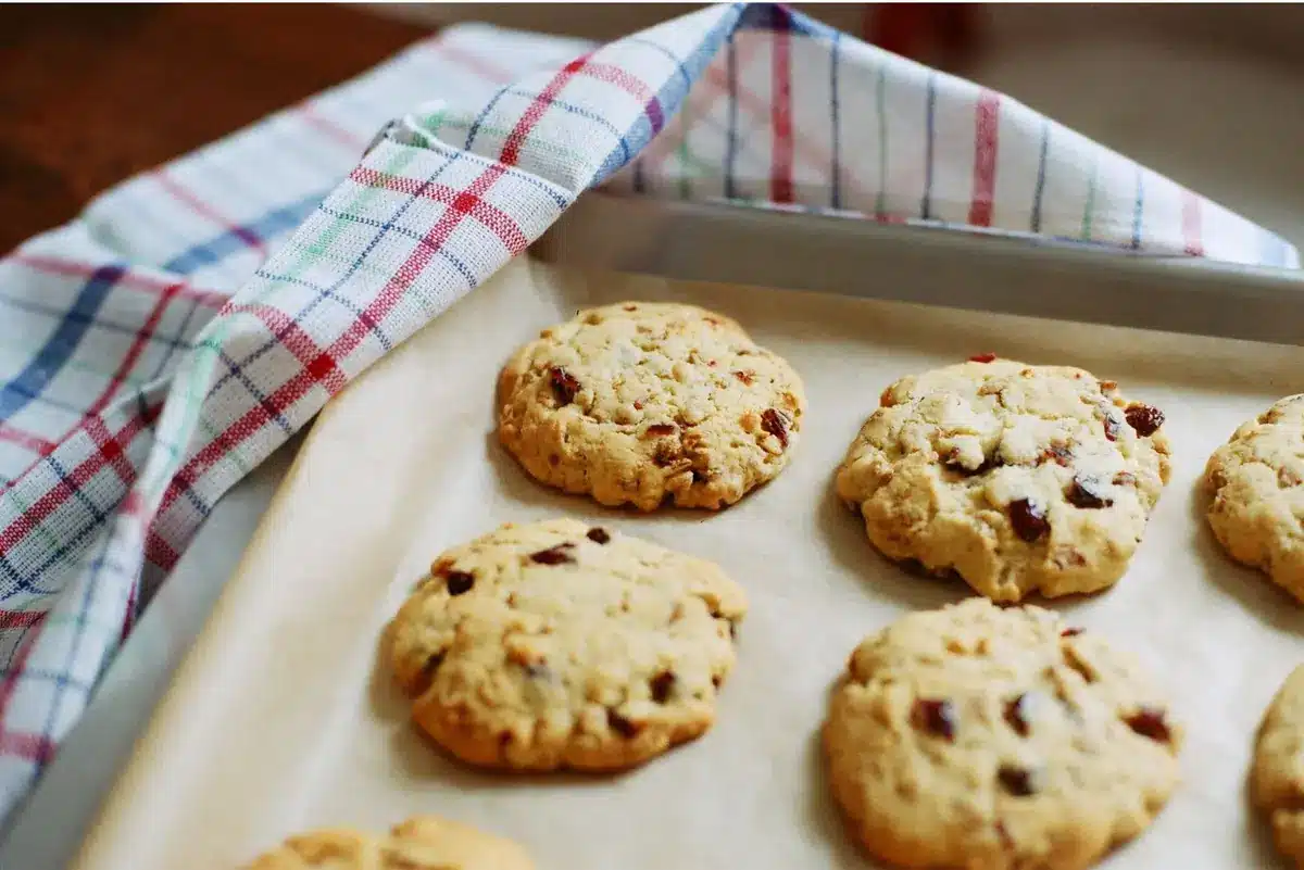 Baked cookies with chocolate pieces on a parchment-lined baking tray