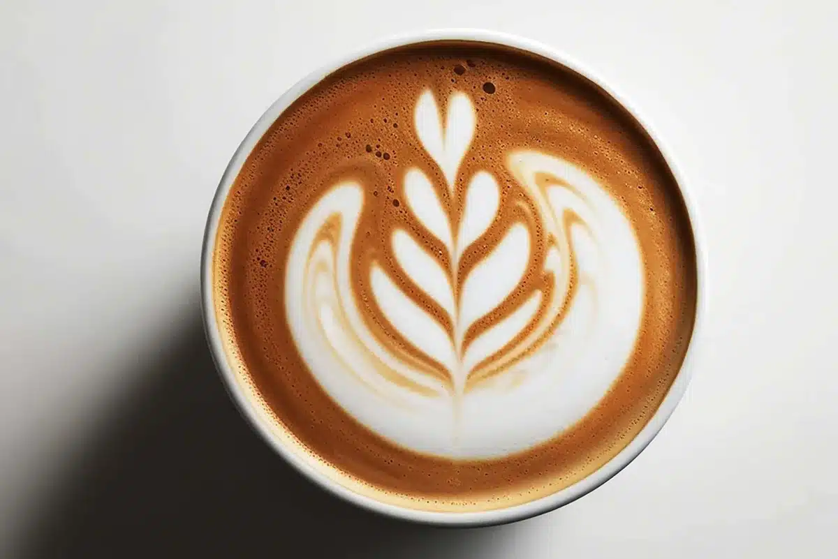Top view of a latte with leaf-shaped milk art in a white cup