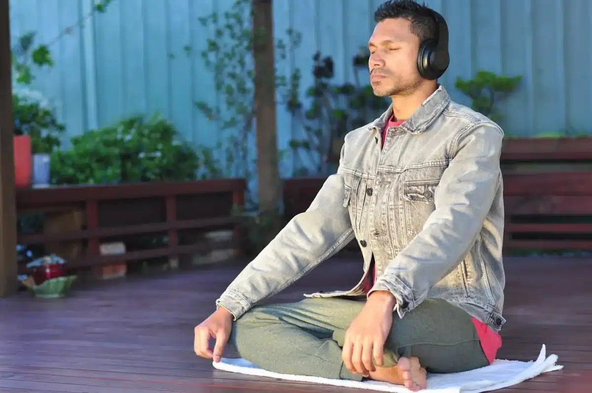 Man sitting cross-legged outdoors wearing headphones