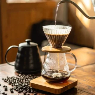 Pour-over coffee dripping into a glass carafe on a wooden table